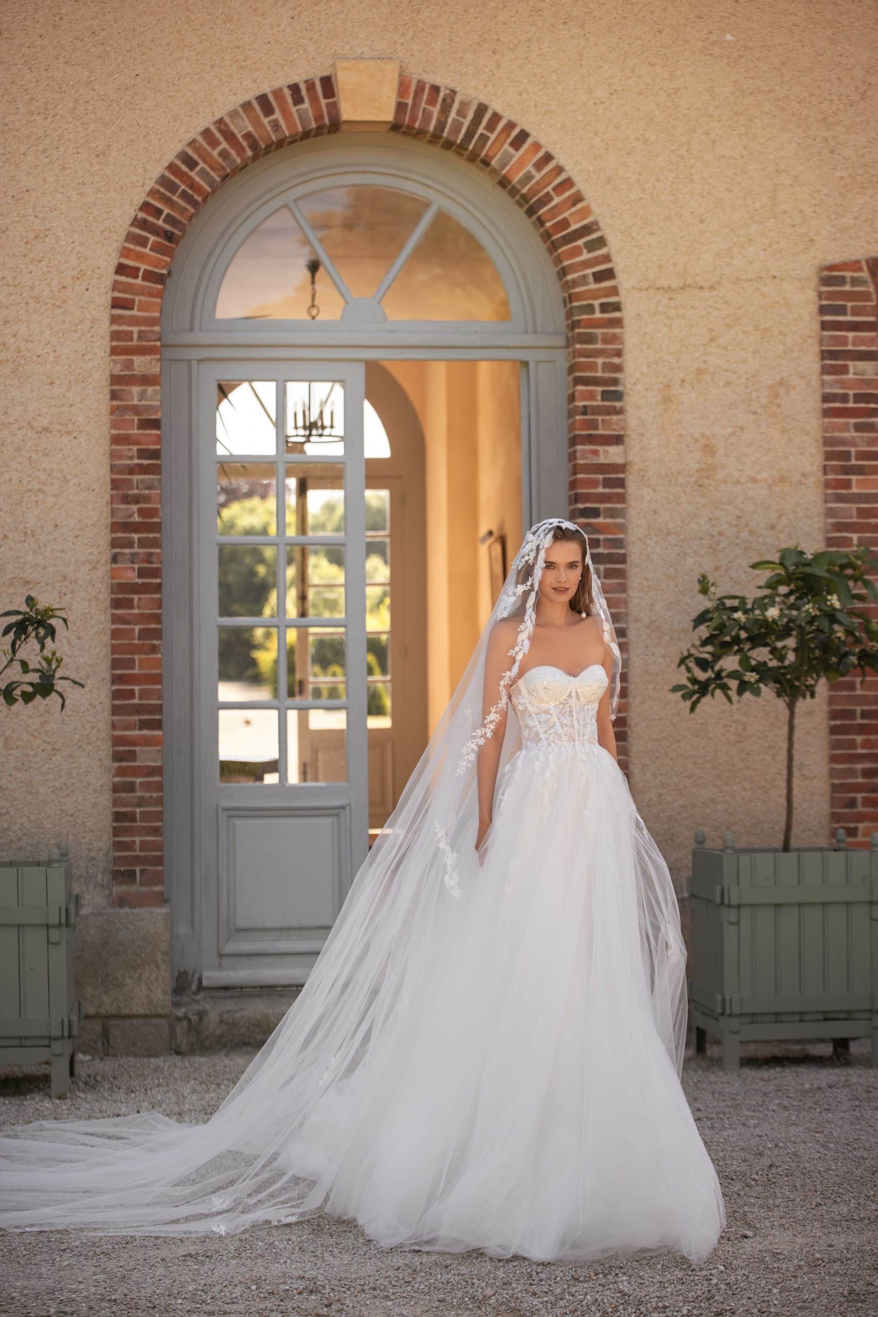 Bild von vorne: weißes Brautkleid mit Glitzer- Spitzenkorsett und Tüllrock und einem langen Schleier