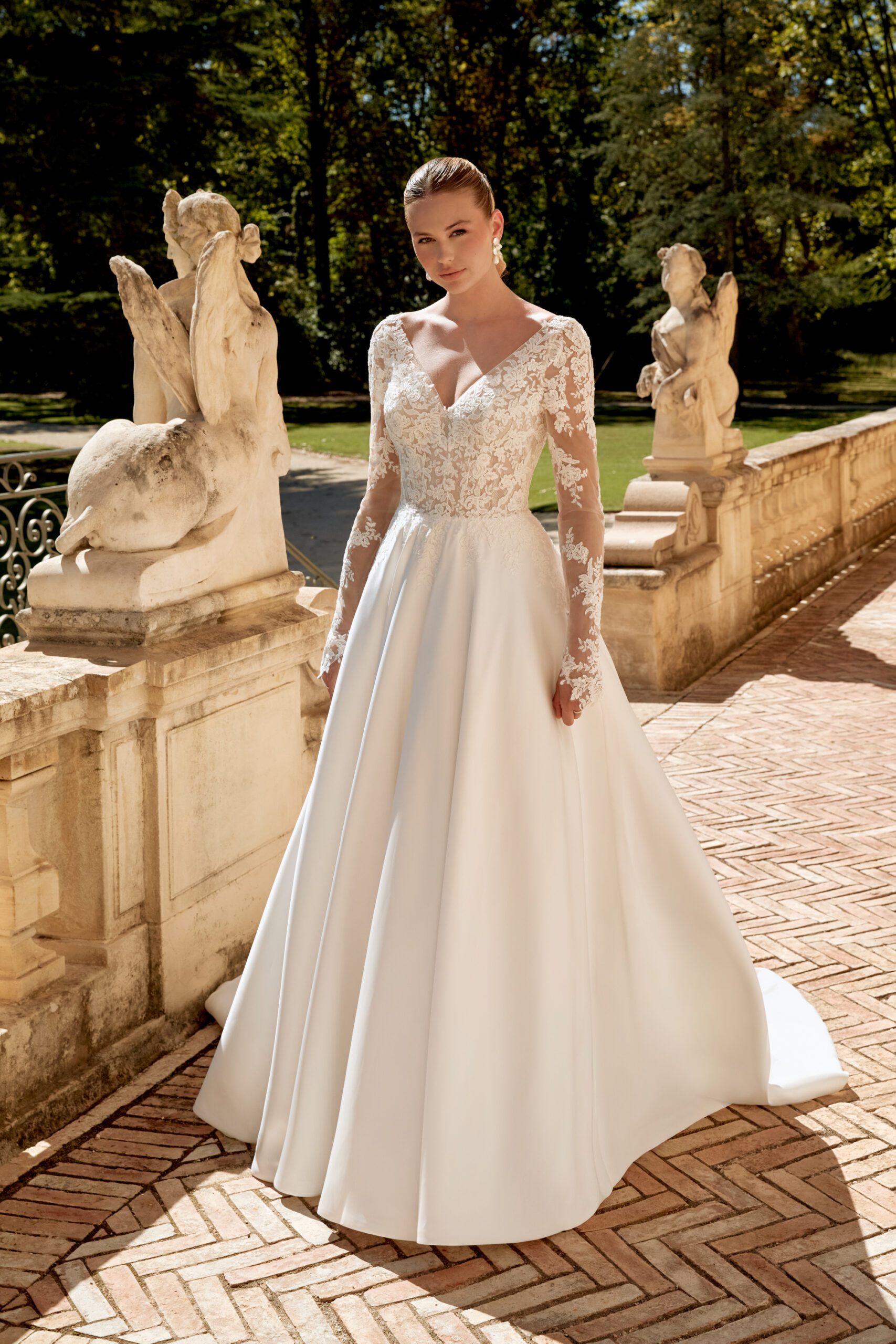 Das Brautkleid hat eine Soutach-Spitze im Oberteil mit Verlauf in den Satin-Rock. Die Ärmel aus Spitze sind abnehmbar, der V Ausschnitt ist sowohl vorne als auch hinten