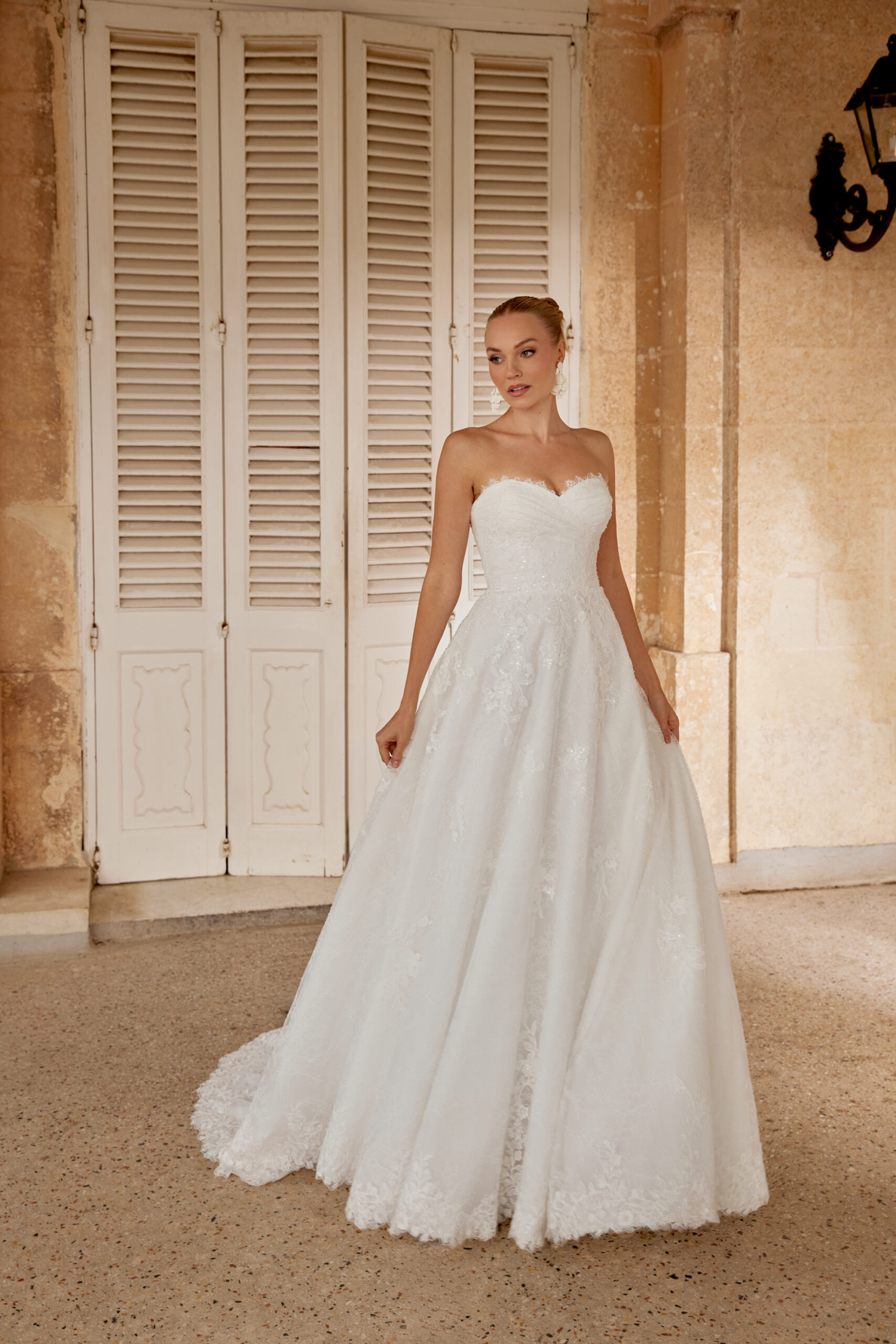 trägerloses Brautkleid aus all-over Chantilly Spitze. Das Oberteil hat schöne Drapierenden und die Schleppe einen Spitzenabschluss