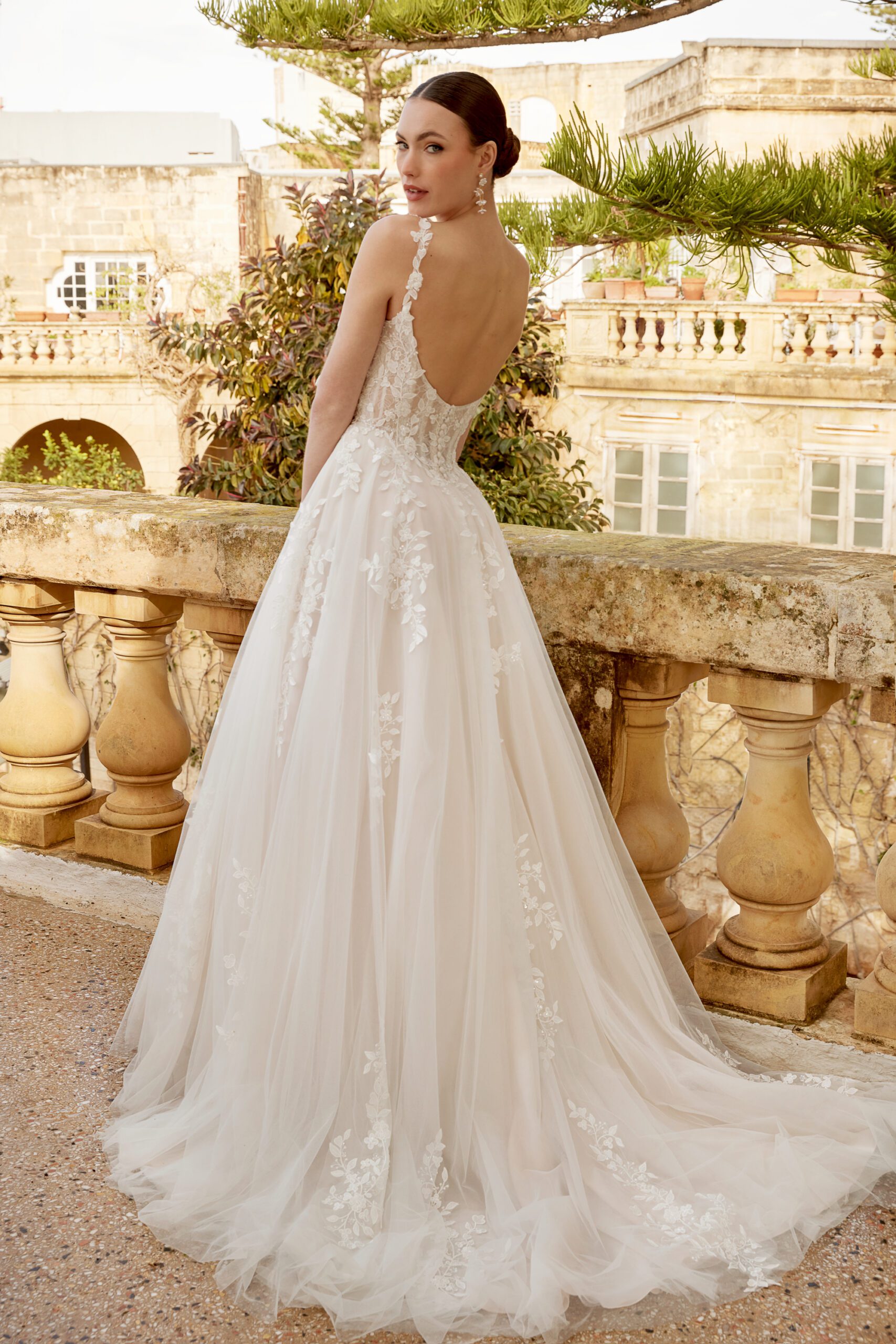 Das Brautkleid ist aus Tüll und mit Blumenapplikationen verziert. Die Spaghettiträger haben die selbe Spitze. Der Ausschnitt vorne ist